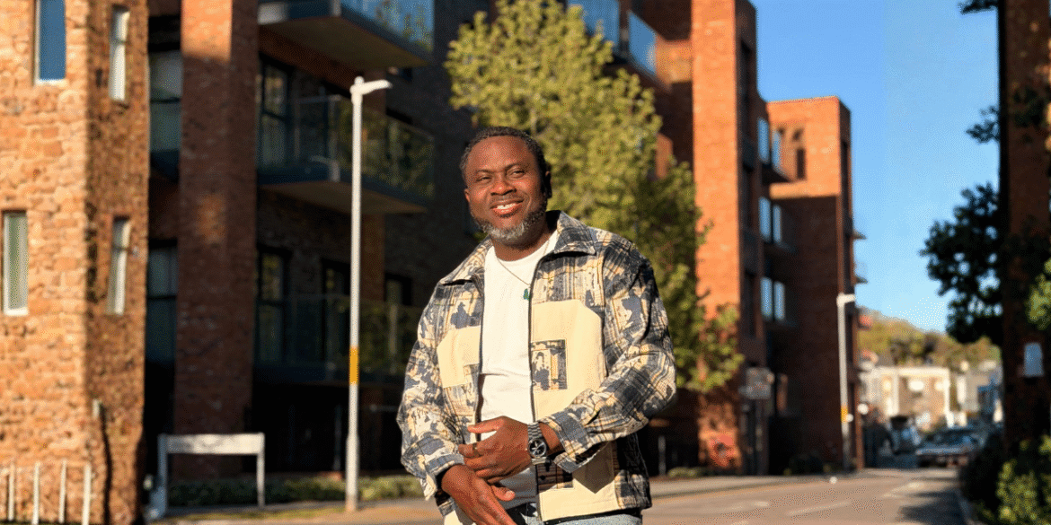 Kenny Ojo smiling outdoors in an urban neighborhood, reflecting confidence, community, and authentic storytelling.