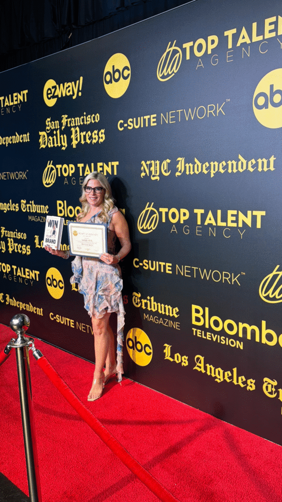 Samara Beth holds her book and award on a red carpet celebrating branding and entrepreneurial achievement.