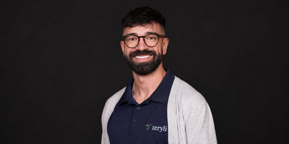 Christopher Molina wearing a Teryli polo shirt and smiling against a black studio background.