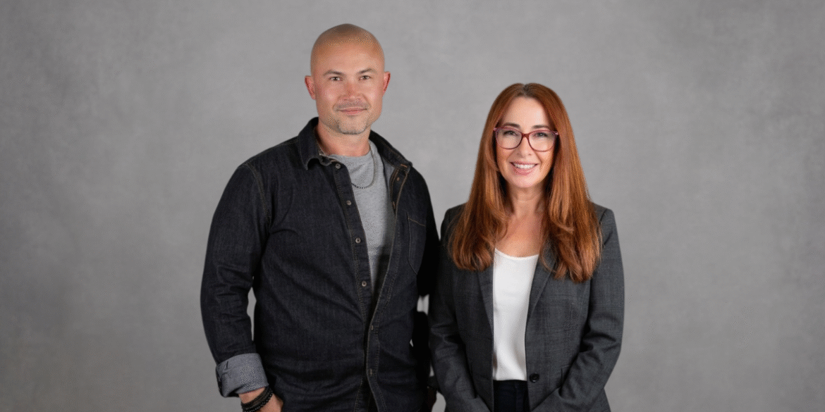 Tyler Pereversoff and Rhian Lois Wight standing together against a gray studio background.