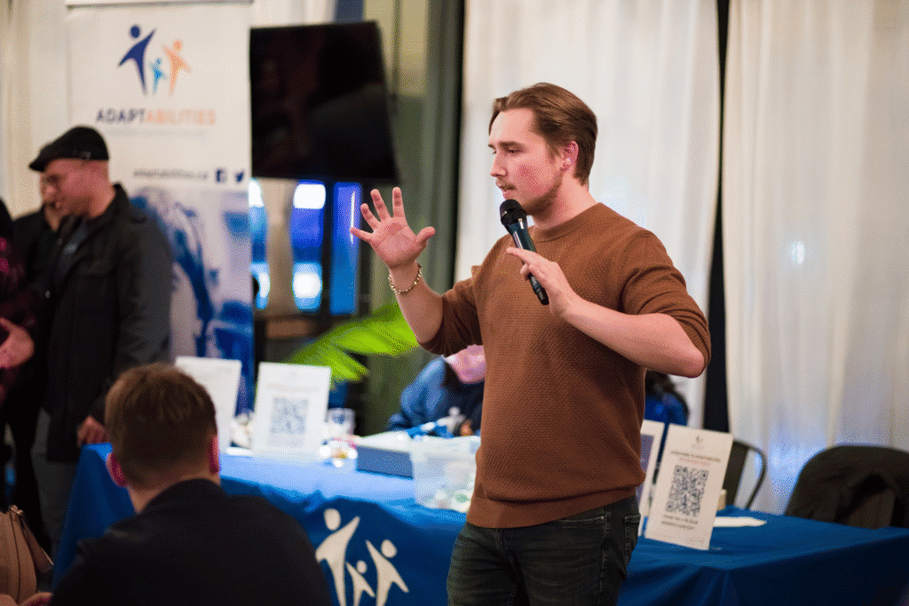 Trystan Keller speaks at a Messed Up Mondays entrepreneur networking event, addressing attendees with a microphone.