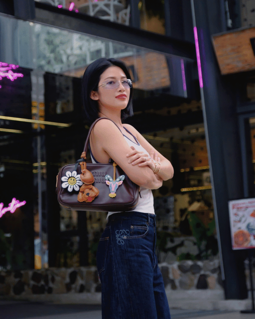 Person carrying a leather handbag decorated with handcrafted leather bag charms.