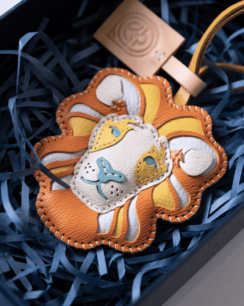 Handcrafted leather lion bag charm in a gift box with branded leather tag.