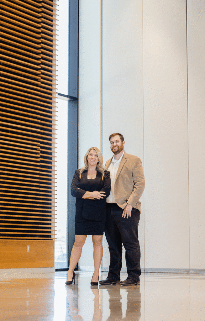 Lauren Foust and Kris Foust standing together in a modern office building.