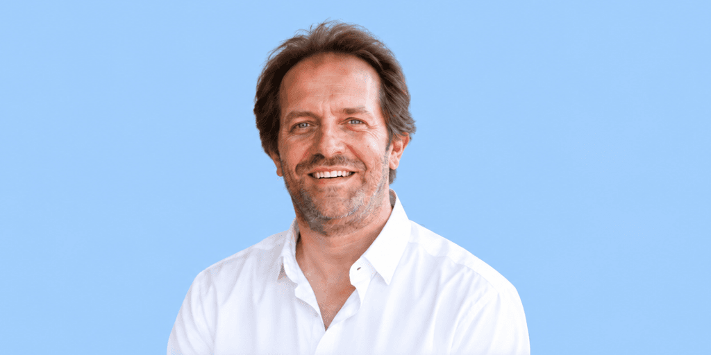 Smiling man in a white shirt against a light blue background
